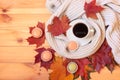 Cup of coffee, wrapped in scarf, macaroon cookies and autumn maple leaves on wooden table. Top view, copy space