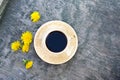 Cup of coffee and yellow dandelion flowers on vintage blue grey wooden background, summer flatlay. Copy space for your text and