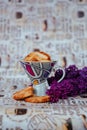 a cup with cookies on the background of a bouquet of lilacs