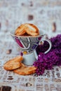 a cup with cookies on the background of a bouquet of lilacs