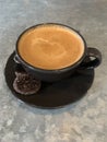 A cup of cortado coffee against a grey patterned background