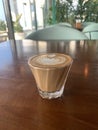 A cup of cortado coffee in a glass on a restaurant terrace