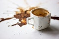 A Cup of custard coffee spilled on a white table background, side view. A beautiful spot from the coffee brew. Fortune