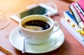 Cup of dark coffee with smart phone and book on wooden background. Coffee can help in your education time