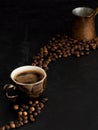 A cup with dark espresso on a black background, steam rises above the cup. Roasted coffee beans are located around a cup of coffee Royalty Free Stock Photo