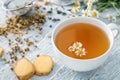 Cup of delicious camomile tea and ginger on wooden table, closeup Royalty Free Stock Photo