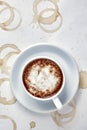 A cup of delicious cappuccino coffee stands on a white background with coffee stains and splashes