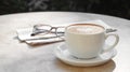 Cup of delicious coffee, glasses and newspaper on beige marble table outdoors, space for text Royalty Free Stock Photo