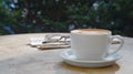 Cup of delicious coffee, glasses and newspaper on beige marble table outdoors, space for text Royalty Free Stock Photo