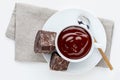 Cup of delicious thick drinkable hot chocolate with pure dark chocolate bars. Bowl with napkin and spoon isolated on white