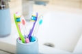 Cup with different toothbrushes near sink