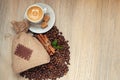 Cup with espresso with coffee beans, burlap sack and cinnamon on light wooden background Royalty Free Stock Photo