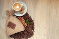 Cup with espresso with coffee beans, burlap sack and cinnamon on light wooden background. With like sign on coffee foam Royalty Free Stock Photo