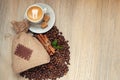 Cup with espresso with coffee beans, burlap sack and cinnamon on light wooden background Royalty Free Stock Photo