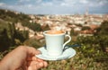 Cup of espresso coffee in hand of tourist and cityscape of Florence in perspective, Italy. Good morning concept