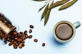 A cup of espresso coffee with an overturned glass jar full of beans on a smooth blue surface Royalty Free Stock Photo