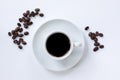 Cup of espresso coffee with saucer and coffee beans scattered around on white background. Top view. Close up image Royalty Free Stock Photo