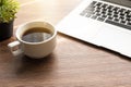 Cup of espresso coffee is on top of wood table with laptop computer and with morning sun light and copy space Royalty Free Stock Photo