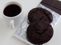 A Cup of espresso and a dark cookie. Bitter chocolate in foil