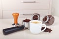 Cup of espresso, holder with ground coffee, tamper and cans of coffee beans on table Royalty Free Stock Photo