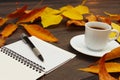 Cup of espresso, open notebook and pen among autumn fallen leaves on wooden background Royalty Free Stock Photo