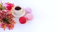 A cup of espresso, red and pink macaroons and a bouquet of alstroemeria on a white background. Festive breakfast.