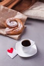 A cup of espresso on a saucer and a layered bun - a classic European or North American breakfast and a love letter in an envelope.