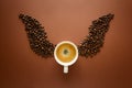 Cup of espresso with wings from coffee beans on brown background. Good morning concept. Top view. Flat lay.