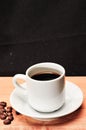 cup of esspreso with a spread of coffee beans on wood serving board