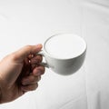 Cup filled with milk or a frothy beverage against a plain white Royalty Free Stock Photo