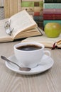 A cup of fragrant black coffee on the table against the background of an open book Royalty Free Stock Photo