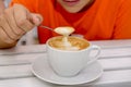 A cup of fragrant cappuccino close-up. a boy scoops up coffee foam with a spoon