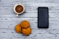 A cup of fragrant coffee, delicious cookies and a mobile phone