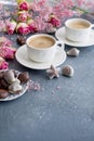 A cup of fragrant coffee in the morning and a bouquet of pink flowers. Chocolate sweets in the form of cockleshells. Shells on the Royalty Free Stock Photo