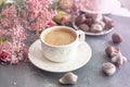 A cup of fragrant coffee in the morning and a bouquet of pink flowers. Chocolate sweets in the form of cockleshells. Shells on the Royalty Free Stock Photo