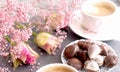 A cup of fragrant coffee in the morning and a bouquet of pink flowers. Chocolate sweets in the form of cockleshells. Shells on the Royalty Free Stock Photo