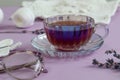 A cup of fragrant tea with lavender branches glasses for vision against the background of needlework and white yarn close-up