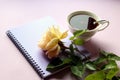 A Cup of fragrant tea with a Notepad and a yellow rose on a purple background, close-up, side view Royalty Free Stock Photo