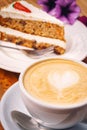 Cup of fresh cappuccino coffee with delicious piece of carrot cake on the wooden table Royalty Free Stock Photo