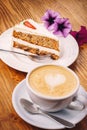 Cup of fresh cappuccino coffee with delicious piece of carrot cake on the wooden table Royalty Free Stock Photo