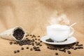Cup of fresh coffee with coffee beans on burlap warm cup on brown background Royalty Free Stock Photo