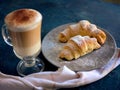 A cup of fresh coffee with croissants on a dark blue background, selective focus Royalty Free Stock Photo
