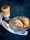 A cup of fresh coffee with croissants on a dark blue background, selective focus Royalty Free Stock Photo