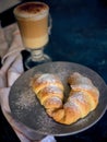 A cup of fresh coffee with croissants on a dark blue background, selective focus Royalty Free Stock Photo