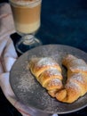 A cup of fresh coffee with croissants on a dark blue background, selective focus Royalty Free Stock Photo