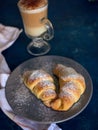A cup of fresh coffee with croissants on a dark blue background, selective focus Royalty Free Stock Photo