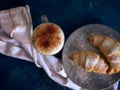 A cup of fresh coffee with croissants on a dark blue background, selective focus Royalty Free Stock Photo