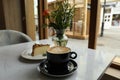 Cup of fresh coffee and dessert on table in cafeteria