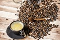 A cup of fresh coffee on a wooden table full of overturned coffee beans from a can Royalty Free Stock Photo