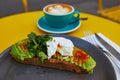 Cup of fresh flat white coffee and delicious toast with avocado and egg Benedict Royalty Free Stock Photo